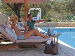 Un hombre y una mujer sentados en una tumbona junto a una piscina. en Villa Valparaiso, en Alhama de Granada