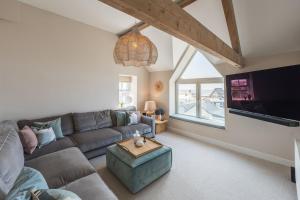 a living room with a couch and a flat screen tv at Wylfa The Upper House & The Hide by Birch Stay in Rhosneigr