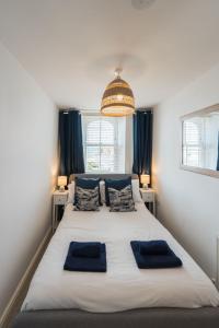 a bedroom with a large white bed with blue pillows at Wylfa The Upper House & The Hide By Birch Stay in Rhosneigr