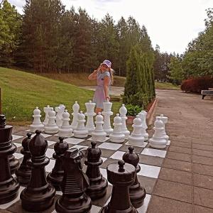 Una mujer parada junto a un tablero de ajedrez gigante en Neciunu sodyba, en Bijūnai