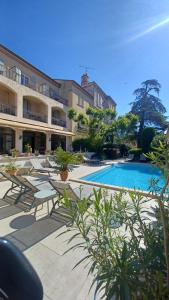 a resort with a swimming pool and tables and chairs at Le Castelet des Alpilles in Saint-Rémy-de-Provence