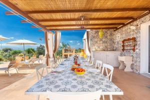 een lange tafel met witte stoelen en een tafel met fruit erop bij Tenuta La Cornola by BarbarHouse in Taurisano