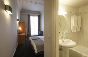 a bathroom with a sink and a bed and a tub at Theater Hotel Leuven Centrum in Leuven