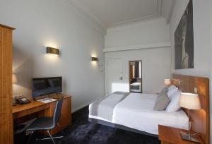 a hotel room with a bed and a desk and a television at Theater Hotel Leuven Centrum in Leuven