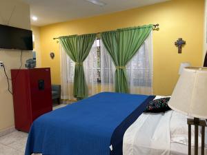 a bedroom with a blue bed and green curtains at Casa Belisario - Pet Friendly in Mazatlán
