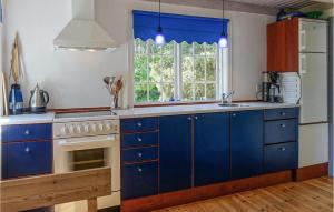 eine Küche mit blauen Schränken, einem Waschbecken und einem Fenster in der Unterkunft Beautiful Home In Nexø With Sauna in Neksø