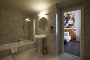 een badkamer met een wastafel, een bad en een spiegel bij Theater Hotel Leuven Centrum in Leuven