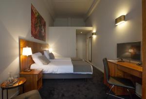 a hotel room with a bed and a desk and a television at Theater Hotel Leuven Centrum in Leuven