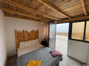 - une chambre avec un lit dans une pièce dotée de fenêtres dans l'établissement EL Faro Surfstay, à Tamri
