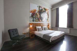 a bedroom with a bed and a chair and a painting at Theater Hotel Leuven Centrum in Leuven