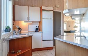 a kitchen with white cabinets and a white refrigerator at Holiday Home Bjerregårdsvej Denm in Bjerregård