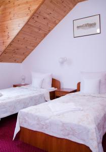 two beds in a room with wooden ceilings at Hotel Nidzki in Ruciane-Nida