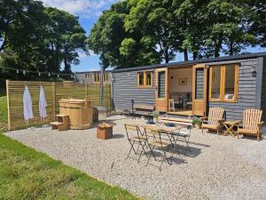 a tiny house with chairs and a table and a patio at Stoodley View Shepherd Huts in Todmorden