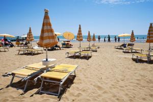 a beach with tables and chairs and umbrellas at APPARTAMENTO MARCONI B2 in Lido di Jesolo