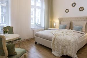 a white bedroom with a bed and a table at Leon Suite Apartments in Leipzig