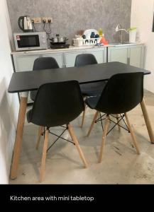 Un área de cocina con una mesa negra y dos sillas. en Triple Room in King Queen Single Bukit Mertajam Alma, en Bukit Mertajam