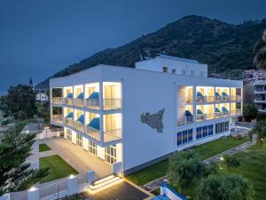 a large white building with a mountain in the background at Riviera Del Sole Hotel Resort Spa in Piraino