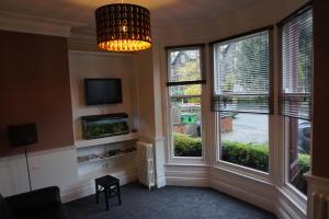 ein Wohnzimmer mit zwei großen Fenstern und einem Kronleuchter in der Unterkunft The Butlers Hotel in Leeds
