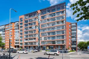 a tall building with cars parked in a parking lot at Best location, cozy and peaceful in Tampere