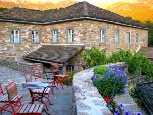 a brick building with red chairs and a table in a garden at Papaevangelou Hotel in Papigko