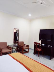 a room with a bed and chairs and a television at Shiva Green Valley Farms in Bikaner