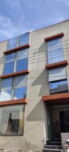 Un edificio con ventanas de vidrio en los costados. en stayEZ Studio Apartments, en Indore