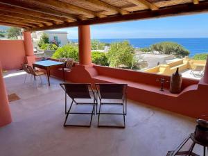 a balcony with chairs and a table and a view of the ocean at Casa Nica, giardino e vista mare in Malfa