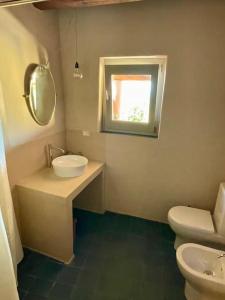 a bathroom with a sink and a toilet and a window at Casa Nica, giardino e vista mare in Malfa