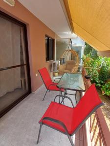 a patio with red chairs and a glass table at Nini's House 1 Nydri - 100m from beach NYDRI TOWN CENTER in Nydri