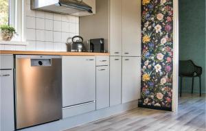 SchoonlooにあるNice Apartment In Schoonloo With Wifiの白いキャビネットと花の壁紙が備わるキッチン