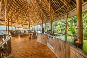 an open kitchen in a straw roofed house with wooden floors at Sunrise House 3bd Bamboo Villa Pool in Bringkit