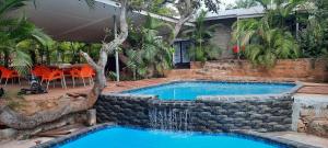 a swimming pool with a waterfall in front of a house at R A GUEST HOUSE PEMBA in Pemba