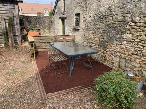 a blue table and chairs in a yard with a stone wall at La frelonniere in Pontlevoy