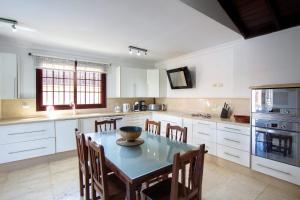 a kitchen with a table and chairs and a kitchen with white cabinets at Villa Jardín de Buda in Arona
