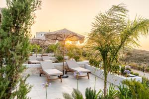 a patio with chaise lounge chairs and palm trees at TERRATORRE in Kefalos
