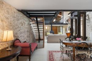 a living room with a stone wall and a table and chairs at The Olive Mill Loft - Oil Mill to Lavish Leisure in Prinés