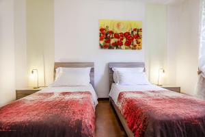 two beds in a room with a painting on the wall at Anthyllis Apartment in Alghero