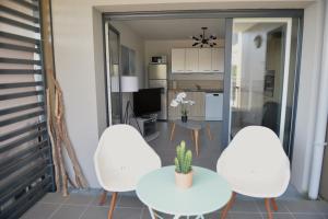 a living room with two white chairs and a table at Appartement cosy et confortable à deux pas du lac in Excénevex