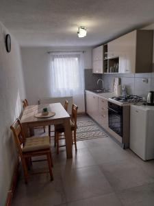 una cucina con tavolo e sedie e una cucina con piano cottura di Apartman Izzy a Kaniža