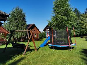 a playground with two swings in the grass at Domki Jaśmin 781-012-181 in Polańczyk