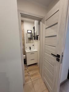 łazienka z białą umywalką i drzwiami w obiekcie Apartament Centrum - Aleja Świętego Jana Pawła II w Kołobrzegu