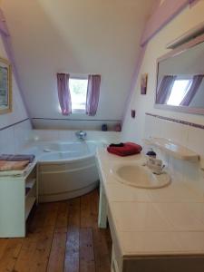 a white bathroom with a tub and a sink at Maison Paimpol in Lanleff