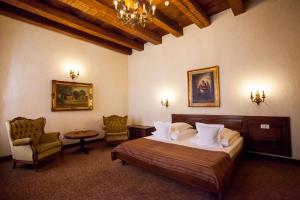 a bedroom with a bed and two chairs and a table at Hotel Bella Muzica in Braşov +33 photos