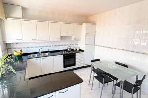 een keuken met witte kasten en een tafel met stoelen bij Apartamento Céntrico en O Grove in O Grove +4 foto's