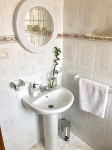 een witte badkamer met een wastafel en een spiegel bij Apartamento Céntrico en O Grove in O Grove