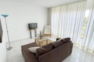 een woonkamer met een bruine bank en een televisie bij Apartamento Céntrico en O Grove in O Grove