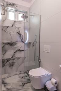 a bathroom with a toilet and a glass shower at Villa Kale in Sarandë +25 photos