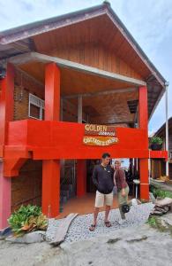 dos personas paradas frente a un edificio en Thenewgoldensunrise, en Tuk Tuk