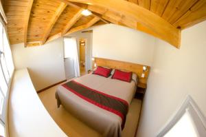 a bedroom with a large bed with red pillows at Del Nomade Hosteria Ecologica in Puerto Pirámides