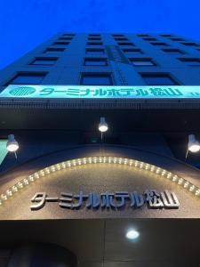 a tall building with a sign in front of it at Terminal Hotel Matsuyama in Matsuyama